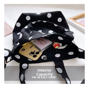 Interior view of black polka dot tote bag with phone, notebook and strawberry charm