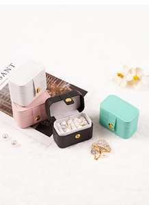 Mini travel jewelry organizer boxes in four colors on a soft white plush background