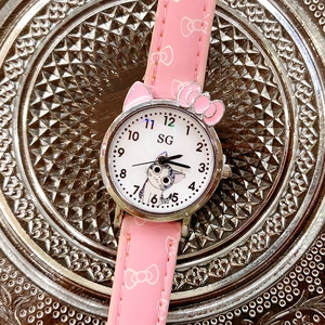 Close-up of pink girls cartoon quartz watch with kitten dial on a silver textured tray