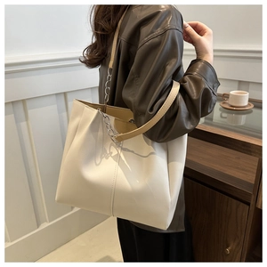 Modella che indossa una borsa tote crema con catena in metallo e tracolla in pelle