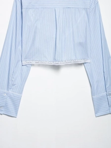 Détail de l'ourlet et des poignets de chemise à rayures bleues avec bordure en dentelle