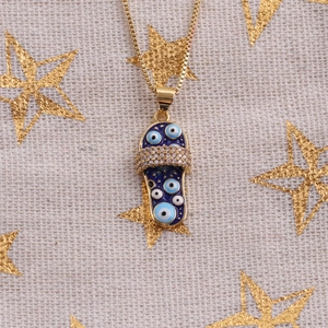 Détail du pendentif pantoufle dorée avec émail bleu œil maléfique et pierres en zircon