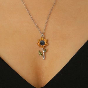Gros plan d'un collier tournesol argenté avec pétales jaunes et feuilles vertes