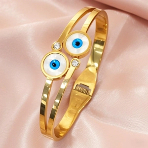 Golden double-ring evil eye open bangle with zircons on pink silk background
