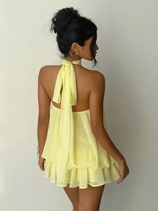 Detail of a backless halter yellow chiffon dress featuring layered ruffle hem and tie-neck
