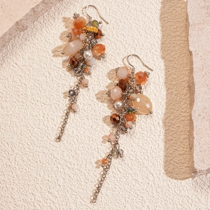 Detailed view of bohemian glass bead tassel earrings with orange and amber tones