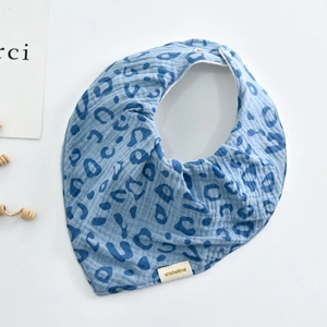 Detail of blue leopard print cotton gauze baby bib with snap button and brand label