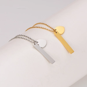 Gold and silver heart and bar pendant necklaces on minimalist white display stand