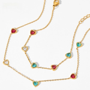 Close-up of golden necklace featuring colorful heart-shaped cubic zirconia and lobster clasp