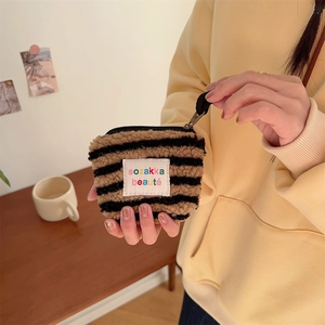 Close-up of a mini plush cosmetic bag featuring black and brown stripes and top zipper