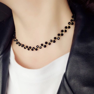 Close-up of black faceted bead choker necklace with gold chain worn by a fashion model