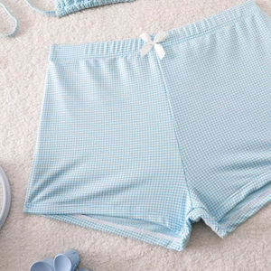 Close-up of blue and white plaid bikini bottoms featuring a delicate white ribbon bow