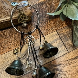 Witch bells door hanger with bronze bells and Celtic pentagram charms on wooden background