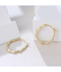Detailed view of the S925 sterling silver hallmark on the golden wavy earring inner band
