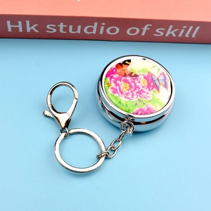 Detailed view of round metal keychain featuring peony and butterfly floral patterns