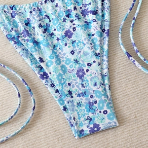 Close-up of floral bikini bottoms with thin side straps and vibrant purple petal patterns