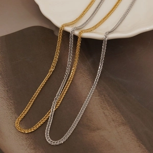 Minimalist stainless steel wheat chain necklaces in gold and silver on a white plate
