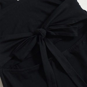 Close-up of a black backless dress showing the bow-tie knot and ribbed fabric texture