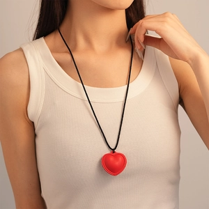 Détail du pendentif cœur rouge texturé sur un long collier en cordon de cuir noir