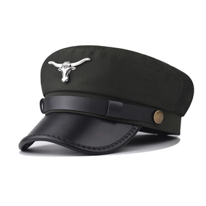 Detail of silver bull head emblem on dark green cotton fiddler cap with leather brim