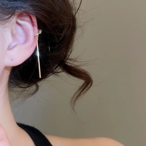 Détail d'un élégant ear cuff doré avec motif de nœud et pendentif long sur le modèle