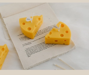 Detailed close-up of yellow cheese-shaped candle with decorative label on vintage paper