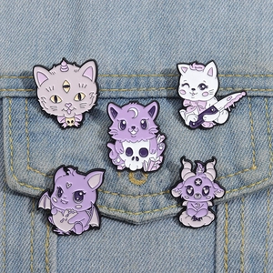 Set of five creepy-kawaii purple cat enamel pins displayed on a blue denim jacket pocket