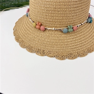 Detailed close-up of woven straw hat with rabbit ear pendants and wavy scalloped edge
