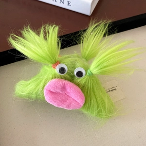 Close-up of a fuzzy green monster hair claw clip with big eyes and pink lips