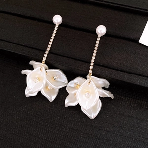 Détail macro de boucles d'oreilles fleuries avec perles blanches et strass étincelants