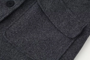 Detail of dark grey wool coat showing high-quality fabric texture and pocket stitching