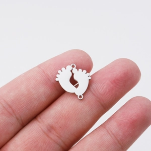 Macro shot of mirror-polished stainless steel baby feet pendant with two connector rings