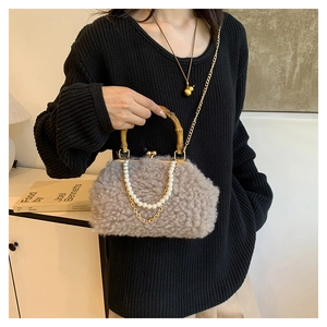 Detail view of plush faux shearling bag with bamboo handle and pearl chain accents