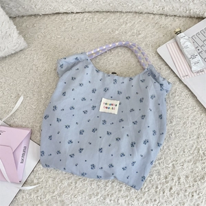 Dettaglio borsa shopper floreale con motivi blu e manici in corda viola su tappeto