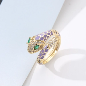 Detail of gold snake ring featuring purple enamel scales and green gemstone eyes