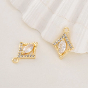 Detail of gold-plated bee pendants with zircon inlay on a textured beige background
