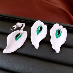 Detail of white flower petal ring and earrings set with green centers and pearls