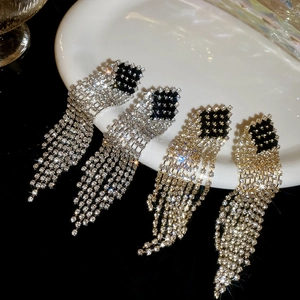 Detail shot of silver and gold tassel earrings with rhinestones on a ceramic dish