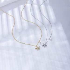 Detailed view of silver and gold starfish pendants with cubic zirconia and pearls