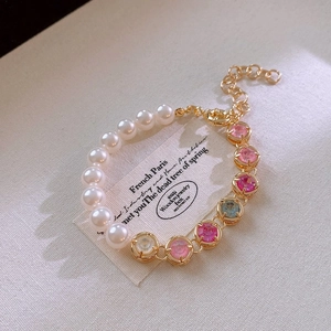 Gros plan d'un bracelet en perles et pierres précieuses avec fermoir mousqueton doré