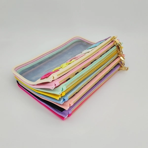 Detail of colorful waterproof PVC toiletry bags with gold metal zippers and transparent windows