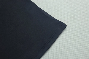 Détail du tissu piqué et coutures précises sur l'ourlet de cet ensemble noir