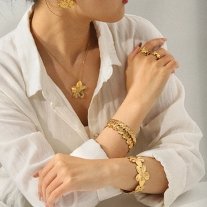 Parure de bijoux élégante en acier inoxydable doré avec fleurs portée par un modèle