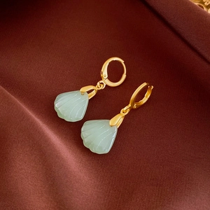 Detailed macro view of shell-shaped natural stone earrings on elegant silk background