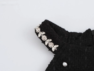 Détail de la bretelle fleur en cristal et perle sur robe dos nu en tweed noir