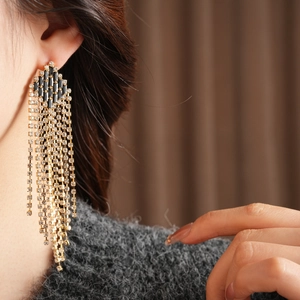 Close-up of elegant long tassel earrings with black stones on a female model