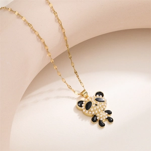 Macro detail of a gold panda pendant with white pearls and black enamel on a fine gold chain