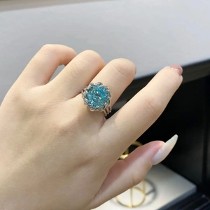 Detailed view of a silver lotus flower ring featuring a sparkling blue gemstone on finger