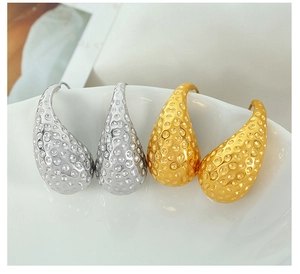 Detailed view of water drop earrings with hammered honeycomb texture in gold and silver