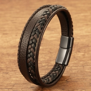 Detail of multi-layer braided leather bracelet with black magnetic metal clasp on wood